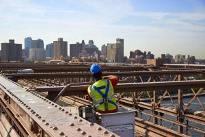 Bridge worker on the Brooklyn Bridge will fall protection gear in compliance with OSHA regulations.